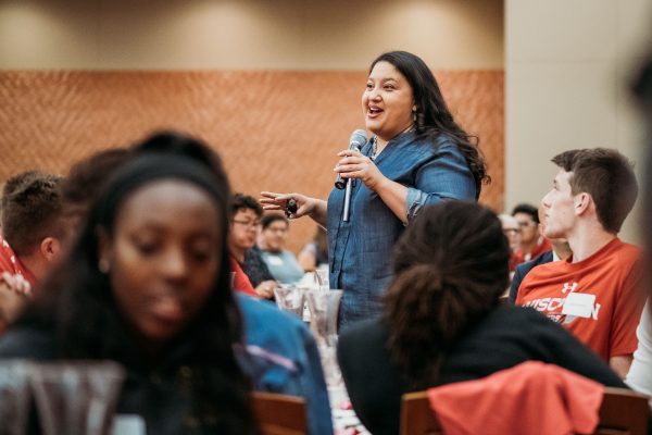 Latina woman speaking while standing among seated students